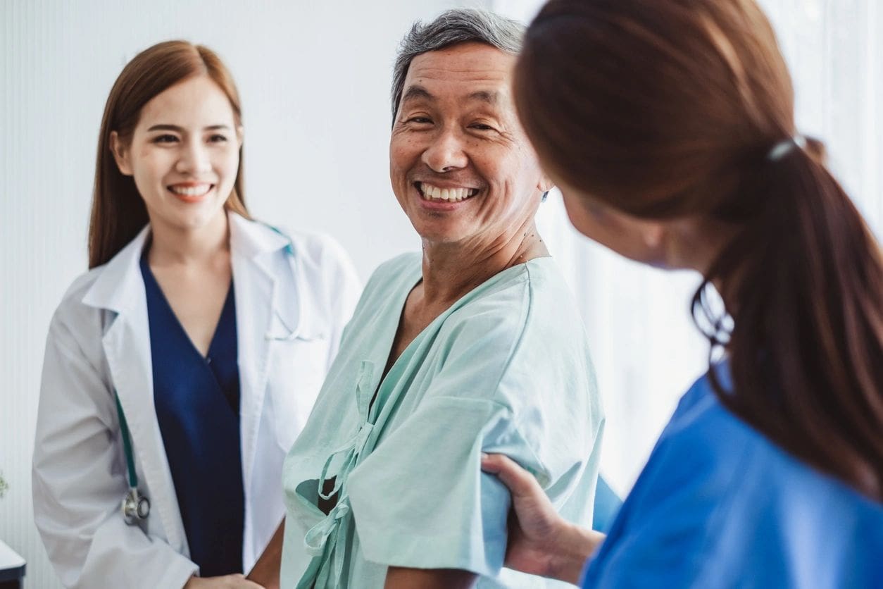 Smiling patient with two healthcare professionals.